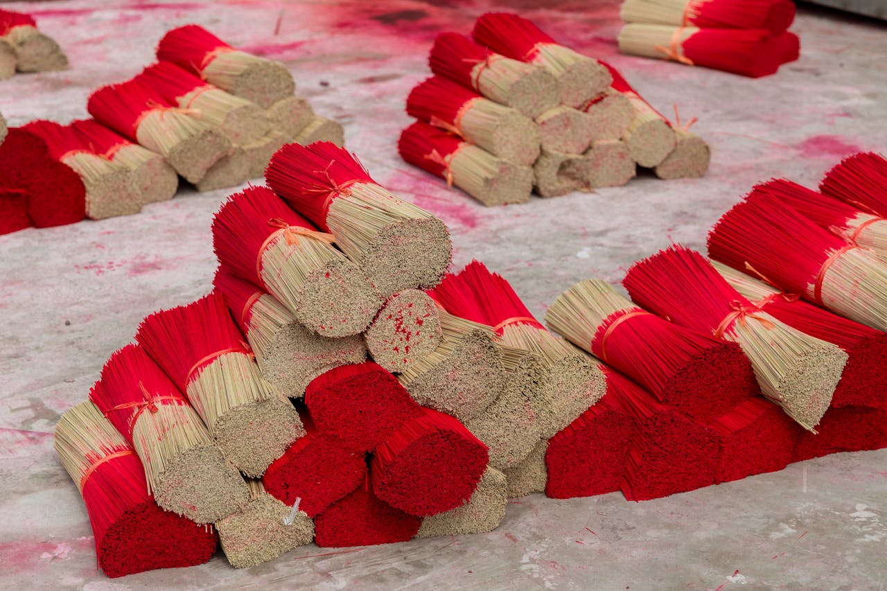 Piles of red-tipped incense sticks on a concrete floor, ready for packaging.