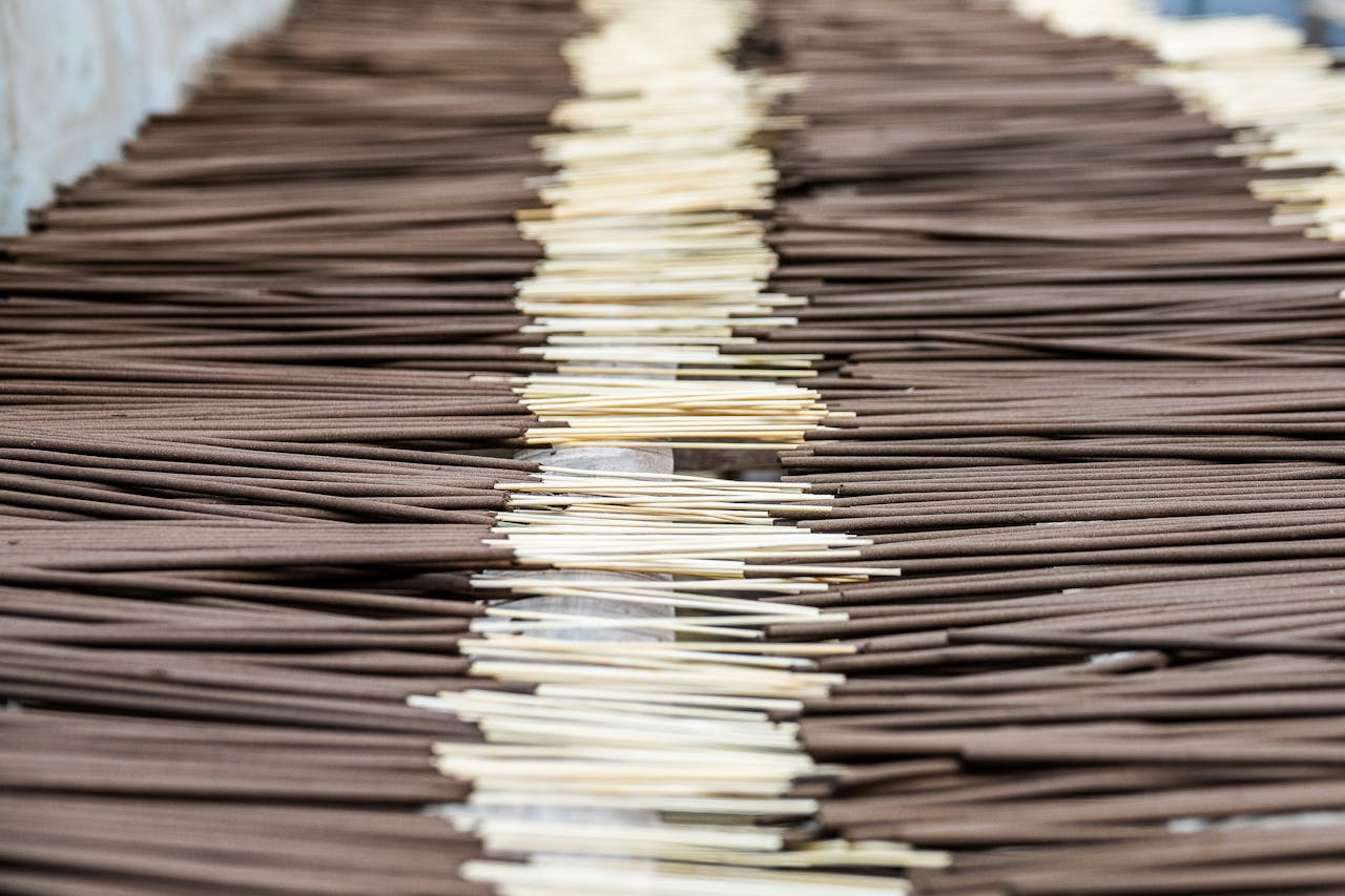 A close-up view of incense sticks aligned in a manufacturing setting, showcasing their distinct arrangement.